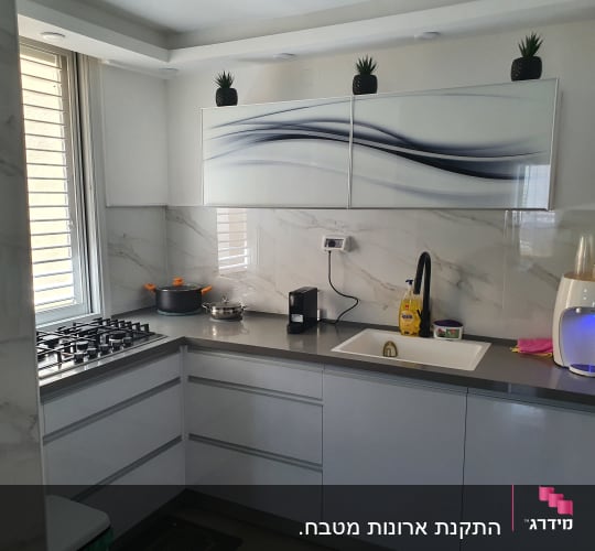 מטבח מודרני עם כיור, כיריים, וסירים על השיש